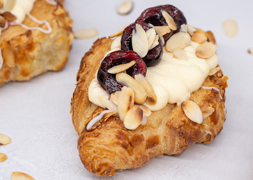 Schulstad Cherry Frangipane Almond Filled Croissant Recipe with cherry jam filling, almond whipped cream cheese frosting, fresh cherries, and slivered almonds